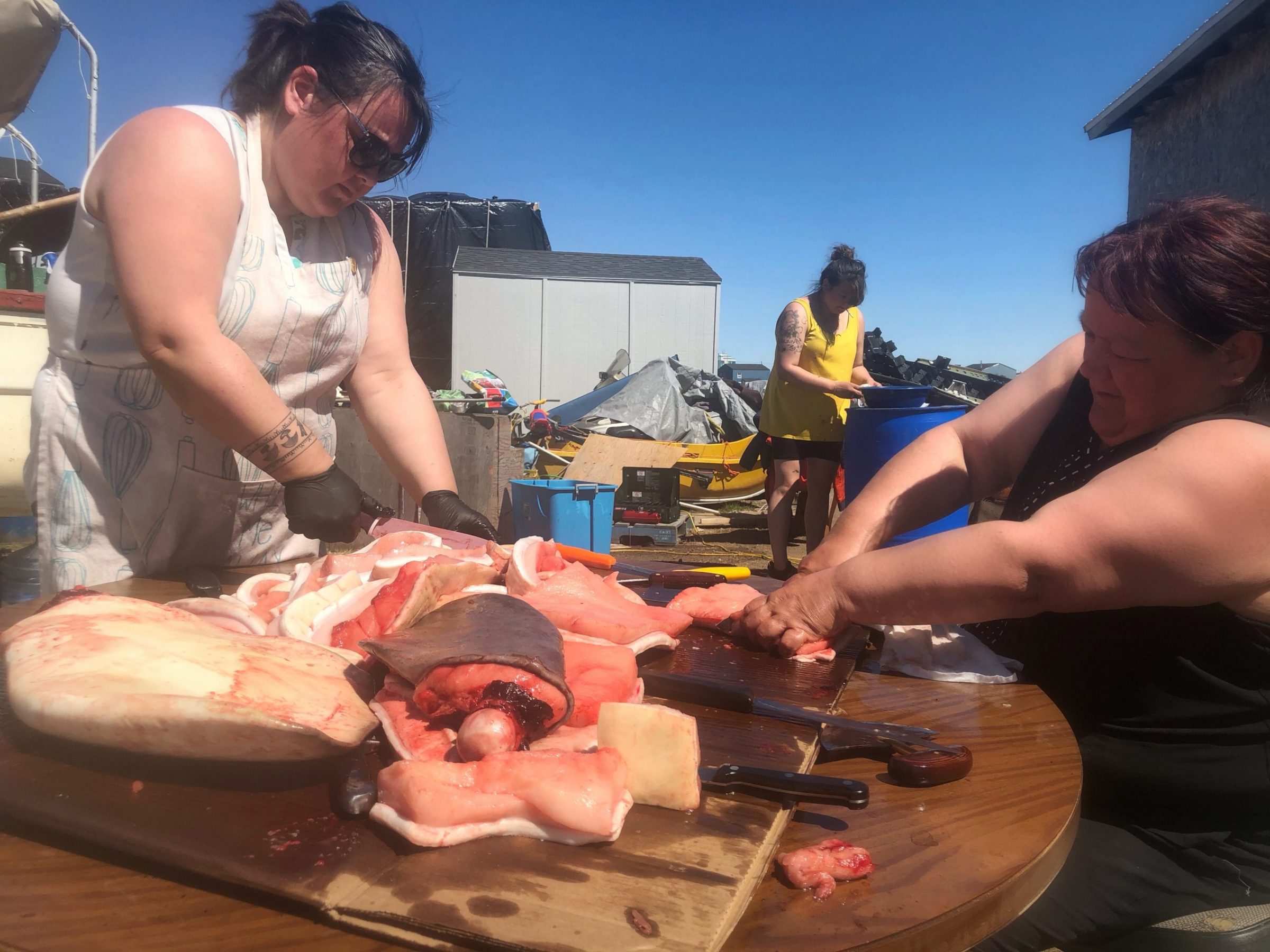 Following a successful beluga hunt, Kuujjuaq residents share maktak on Sunday, June 21, on National Indigenous Peoples Day. Here, hunter Simeonie Berthe’s wife Betsy (right) and daughter Julie-Ann (left) are seen cutting up maktak. (Photo by Isabelle Dubois)