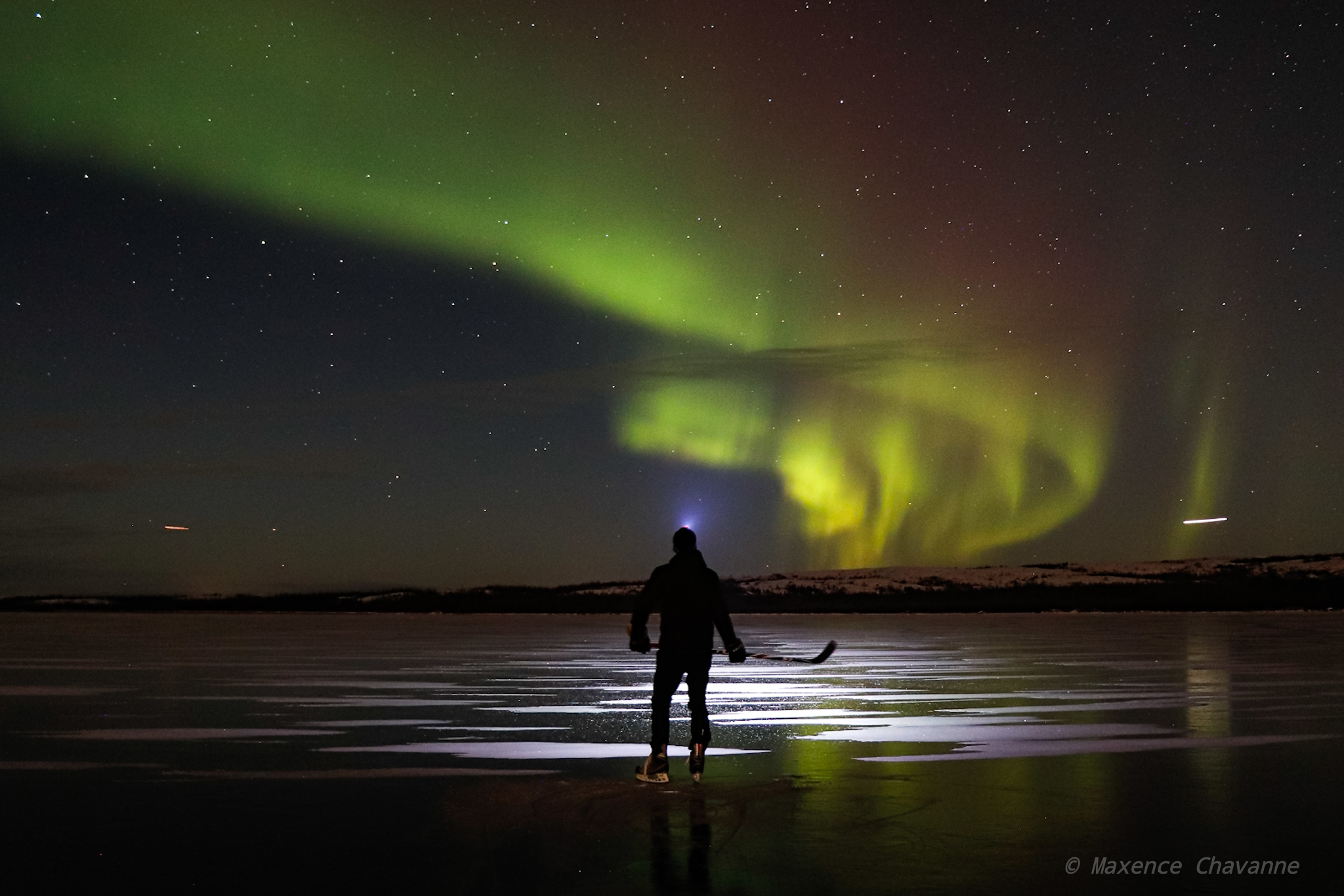 The northern lights glow above a hockey player on a frozen Stewart Lake by Kuujjuaq on Nov. 11. (Photo by Maxence Chavanne)