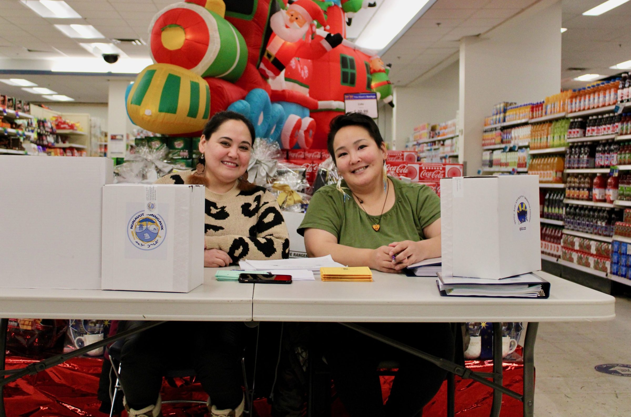 Annabella Piugattuk, left, and Tanya Tucktoo work at a booth at Iqaluit’s Northmart for advance voting in the Qikiqtani Inuit Association and Nunavut Tunngavik Incorporated elections. The elections take place Monday. (Photo by David Lochead)