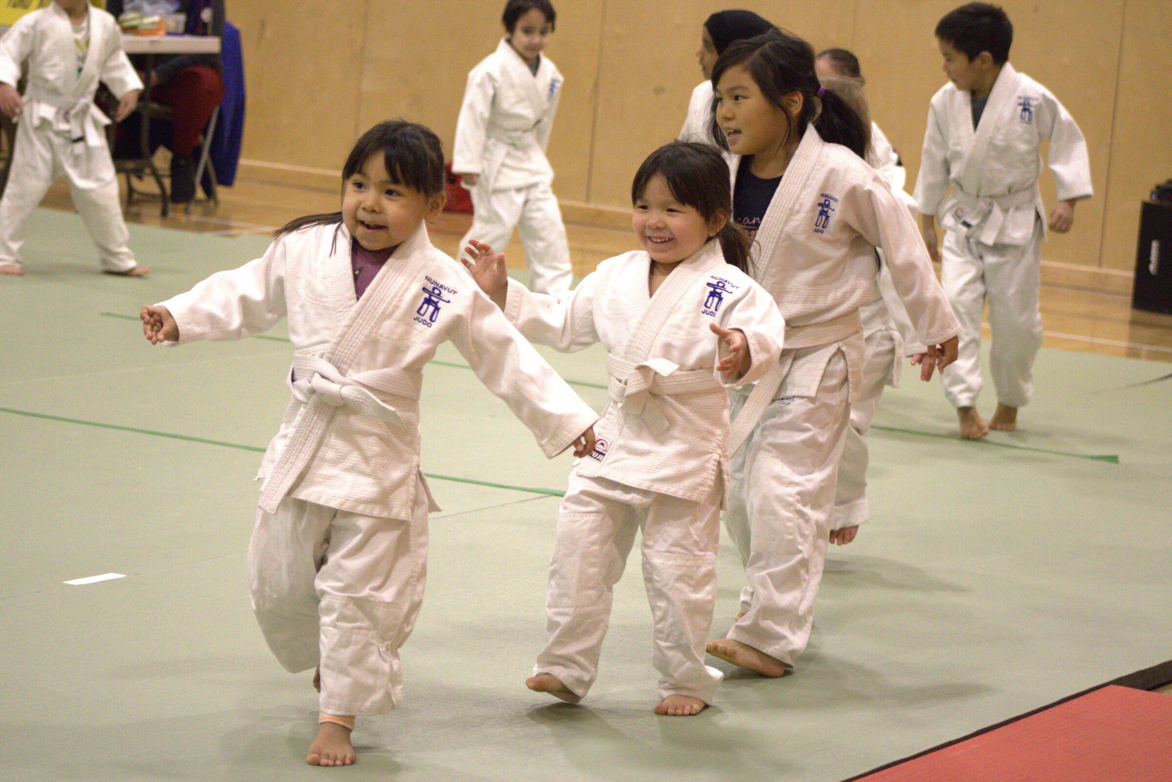 Jimmy Baasch, left, Kylie Kay and Oloota Shaa run to their judo instructor during a Judo Nunavut tournament Saturday at Aqsarniit Middle School in Iqaluit. More than 90 athletes aged five to 18 participated in the event. The organization raised $1,450 for future tournament travel through a bake sale and raffle. (Photo by Daron Letts)